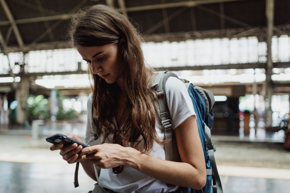 Commuter checking a phone for travel updates while waiting at a bus stop