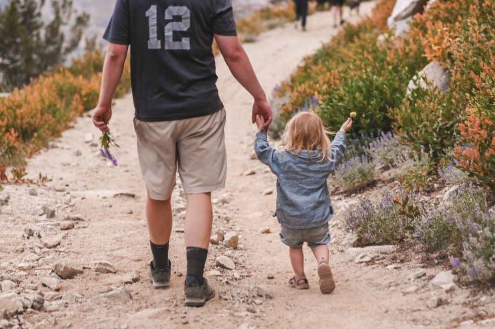 Parent holding a child's hand while walking through a housing estate